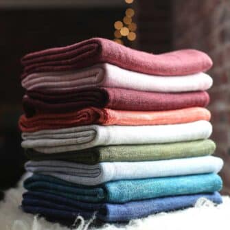 Swans Island Company's Kennebunk Wrap. A luxurious knit travel wrap made with a silky soft Tussah silk / Merino wool blend. Hand-dyed colors have subtle variegation. 100% Made in USA. Only available at Swans Island Co. Shown here in an array of 17 beautiful colors.