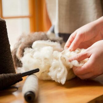 Swans Island Company's Island Collection is handwoven in Northport, Maine using single-origin wool from Longcove Farm on Vinalhaven Island, Maine. Shown here, raw fleece and yarn spun from the undyed brown and white fleece.