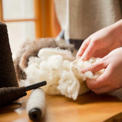 Swans Island Company's Island Collection is handwoven in Northport, Maine using single-origin wool from Longcove Farm on Vinalhaven Island, Maine. Shown here, raw fleece and yarn spun from the undyed brown and white fleece.