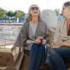 Women wearing capes and laughing while enjoying drinks outside by the harbor