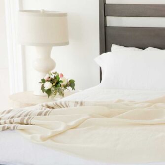 Swans Island Grace Blanket. Handwoven in Maine. 100% wool. Shown here in natural with brown stripes on a king bed.