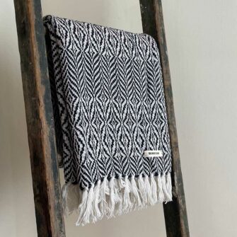 Swans Island's Starburst Throw blanket is woven in Maine with 100% American cotton and features a hand-tied fringe.