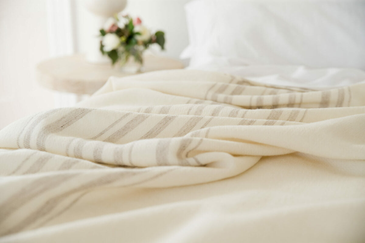 A detail of Swans Island's classic Grace blanket, handwoven with undyed natural wool with a traditional striped border in undyed grey.