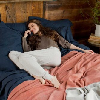 Swans Island Company's Relaxed Linen Sheet Set. 100% French linen made in the USA, breathable, soft and regulates temperature as you sleep. Shown here in Midnight blue with our handwoven Katahdin Blanket in Bittersweet.