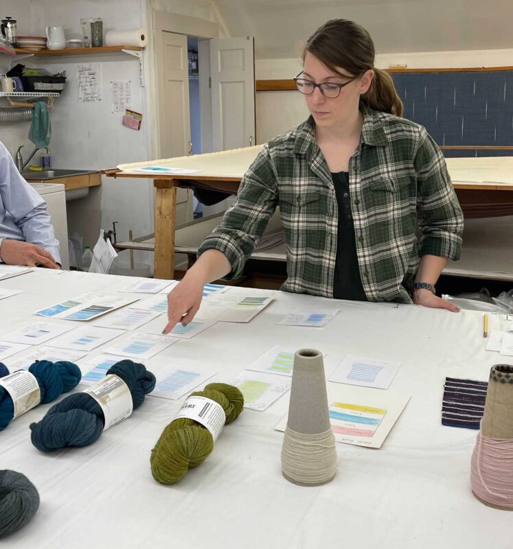 Woman pointing to pencil sketches on a table, for Swans Island Co. Ltd. Edition Ocean Throws.