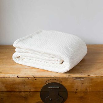 Swans Island Company's Charisma Blanket. Soft 100% Cotton blanket with woven herringbone texture. Made in USA with 100% American cotton. Shown here in Natural