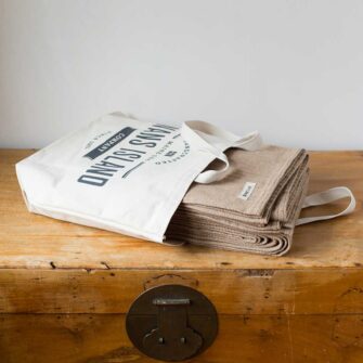 Swans-Island Company's Cashmere Mini-Cable Blankets are woven in Maine with a soft blend of 70% American cotton + 30% Cashmere Shown here in Hazlenut, each blanket comes in our signature canvas tote.