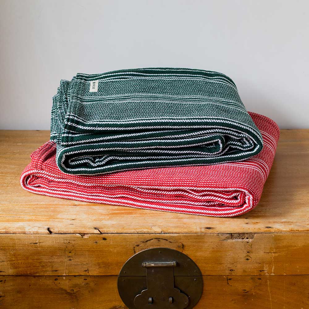 Swans Island Company's Cotton Pick Stripe Blanket. Soft 100% Cotton blanket with yarn-dyed woven stripes. Made in USA with 100% American cotton. Shown here in holiday Red and Green.