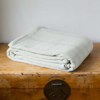 Swans Island Company's Savannah Blanket. Soft 100% Cotton blanket with woven herringbone texture. Made in USA with 100% American cotton. Shown here in Bayleaf.