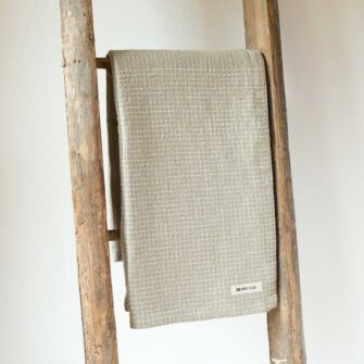 Swans Island Company's Pinstripe Linen Throw. Made in USA, has an allover subtle pinstripe design highlighted with a checked border. Linen Cotton blend. Shown here in Linen color.