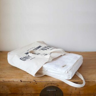 Swans Island Company's Bedford Cotton Blanket. Soft 100% Cotton blanket with a small banded check texture. Made in Maine, USA with American cotton. Each blankets comes in our signature cotton canvas tote.
