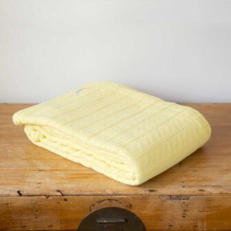Swans Island Company's Bedford Cotton Blanket. Soft 100% Cotton blanket with a small banded check texture. Made in Maine, USA with American cotton. Shown here in Light Blue.