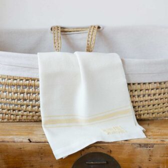 Swans Island Company's classic Grace Baby Blankets. Handwoven in Maine with soft organic merino wool yarns. Pure undyed organic merino wool with an assortment of rich hand-dyed stripe colors. Each blanket comes in a beautiful presentation gift box, perfect for gifting. Shown here in White with Honey stripes.
