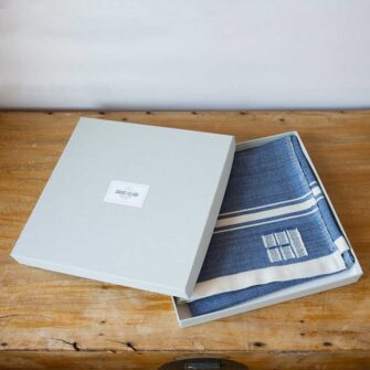 Swans Island Company's Grace Modern Baby Blankets. Handwoven in Maine with soft organic merino wool yarns in an assortment of rich hand-dyed colors. Each blanket comes in a beautiful presentation gift box, perfect for gifting. Shown here in indigo.