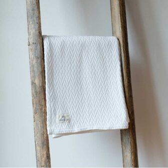Swans Island Company's Charisma Throw. Soft 100% Cotton blanket with woven herringbone texture. Made in USA with 100% American cotton. Shown here in White.