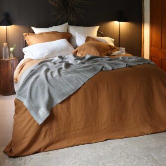 Swans Island Company's Golden Hour Bedding Bundle - Includes 1 Classic Linen Sheet Set in Ivory + 1 Relaxed Linen Duvet Set in Golden Honey. 100% French linen made in the USA, breathable, soft and regulates temperature as you sleep. Shown here with a signature Swans Island handwoven Heritage blanket.