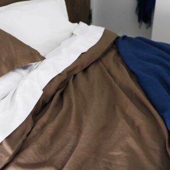 Swans Island Company's Coastal Cottage Bedding Bundle. Includes 1 Classic Linen Sheet Set in white + 1 Relaxed Linen Duvet Set in Mocha. Shown here with our handwoven Katahdin blanket in Indigo color.