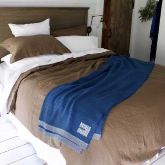 Swans Island Company's Coastal Cottage Bedding Bundle. Includes 1 Classic Linen Sheet Set in white + 1 Relaxed Linen Duvet Set in Mocha. Shown here with our handwoven Katahdin blanket in Indigo color.