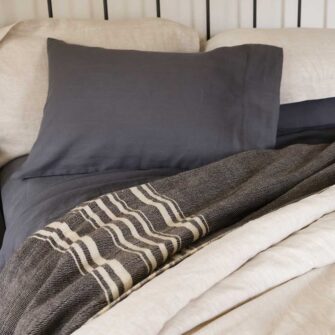 Swans Island Company's Stone Coast Linen Bedding Bundle. Includes 1 Relaxed Linen Sheet Set in Obsidian + 1 Classic Linen Duvet Set in Flax. Shown here paired with a Signature signature handwoven Grace Winter wool blanket in Charcoal.
