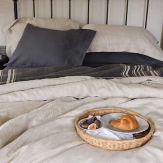 Swans Island Company's Stone Coast Linen Bedding Bundle. Includes 1 Relaxed Linen Sheet Set in Obsidian + 1 Classic Linen Duvet Set in Flax. Shown here paired with a Signature signature handwoven Grace Winter wool blanket in Charcoal.