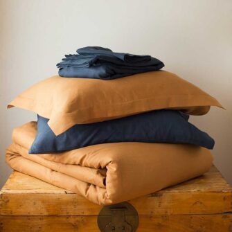Swans Island Company's Harvest Linen Bedding Bundle. Combines a Relaxed Linen Sheet set in Midnight Blue with a Relaxed Linen Duvet Set in Golden Honey for a warm inviting bedroom retreat. Our French linen bedding is stitched in the USA.