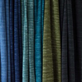 Swans Island Company's Kennebunk Wrap. A luxurious knit wrap made with a silky soft Tussah silk / Merino wool blend. Hand-dyed colors have subtle variegation. 100% Made in USA. Only available at Swans Island Co. Shown here an array of beautiful hand-dyed blue and green colors