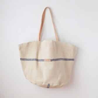 Swans Island Company's Market Basket Tote by Govou. Handcrafted in Spain from vintage linen grain sacks. Each bag is unique. Shown here in natural with blue stripes, leather straps.