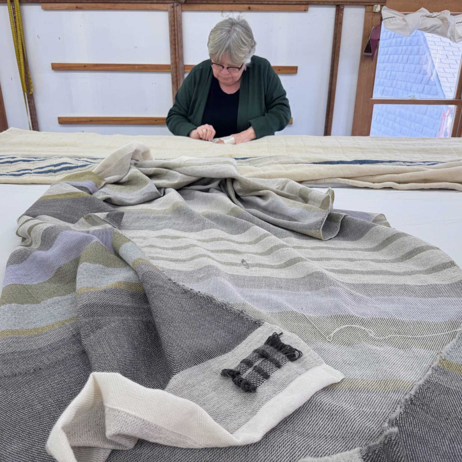 woman stitching weaver's mark on throw