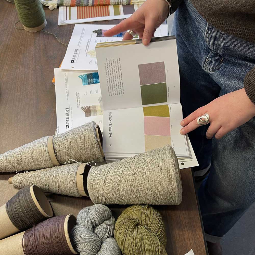 yarn and swatchbook on table with hands