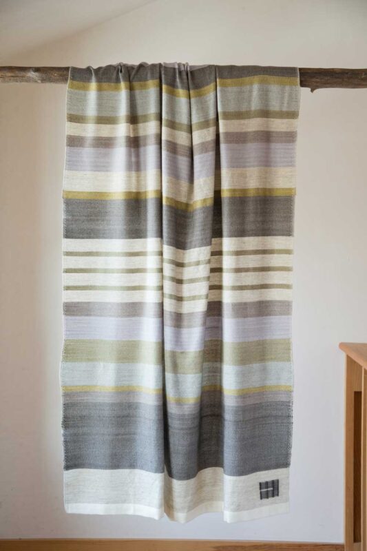 handwoven striped throw handing on pole
