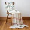 Swans Island Company's Rainbow Throw. All natural organic merino wool handwoven with band of 7 all-natural dyed stripes. Made in Maine. Shown in Natural with Brights.
