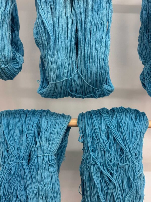 Swans Island x Pierrepont Hicks Wool Camp Blanket - handwoven in Maine with hand-dyed wool. Inspired by camp blankets of the past, woven in colors of today - a bold turquoise ground with shades of orange stripes in the borders. Hand-dyed turquoise wool yarn hangs to dry.