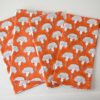 Swans Island Seema Napkins by Soil to Studio. Block printed by hand in India with bright playful patterns. Shown here in Poppy Orange with natural and blue flowers. Set of four.
