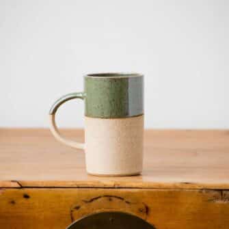 Swans Island Company's Tall Dipped Mugs are handcrafted with stoneware pottery dipped with a food-safe earthy glaze on top. Made in Maine. Shown here in Olive.
