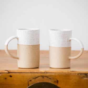 Swans Island Company's Tall Dipped Mugs are handcrafted with stoneware pottery dipped with a food-safe earthy glaze on top. Made in Maine. Shown here in White., Set of two.