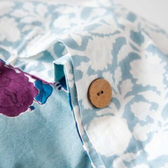 Swans Island Company's Sara Duvet Cover by Soil to Studio. Block printed by hand in India with bright playful patterns. Shown here in Denim with roses. Button closure detail.