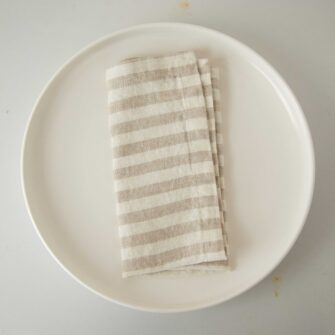 Swans Island Company's linen napkins by Linen Tales, made with 100% European Linen Oeko-Tex® and EUROPEN FLAX® certified. Made with stonewashed soft linen with mitered corners for a crisp edge. Shown here in Natural White Stripe.
