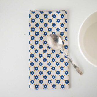 Swans Island Company's Pia Napkins by Soil to Studio. Block printed by hand in India with bright playful patterns. Shown here in Natural with yellow and blue.