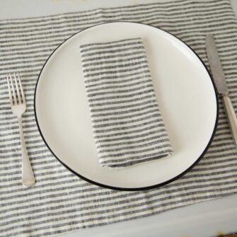 Swans Island Company's linen placemats by Linen Tales, made with 100% European Linen Oeko-Tex® and EUROPEN FLAX® certified. Made with stonewashed soft linen with mitered corners for a crisp edge. Shown here in Thin Black Stripe with matching linen napkin.