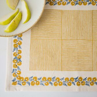 Swans Island Company's Shika Placemat by Soil to Studio. Block printed by hand in India with bright playful patterns. Shown here in Natural with daffodil yellow.