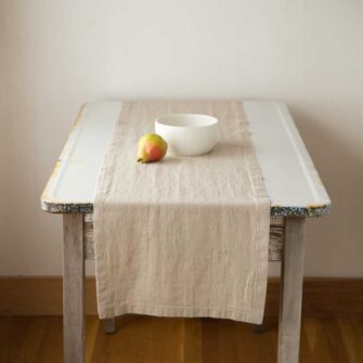 Swans Island Company's linen table runner by Linen Tales, made with 100% European Linen Oeko-Tex® and EUROPEN FLAX® certified. Made with stonewashed soft linen with mitered corners for a crisp edge. Shown here in Natural Flax color.