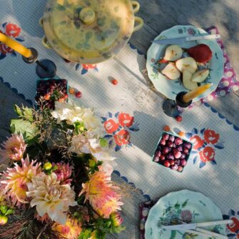 Swans Island Kamala Table Runner by Soil to Studio. Block printed by hand in India with bright playful patterns. Shown here in Natural Tan check with Red Roses.