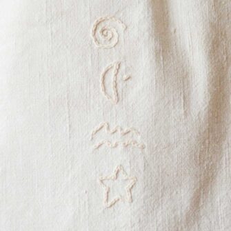 Swans Island Company's Anya Embroidered Tote bag by Govou. Upcycled antique grain sacks are reimagined into unique tote bags. This one features hand-stitched seashore embroidery motifs. Shown here in natural colorway. Swatch detail