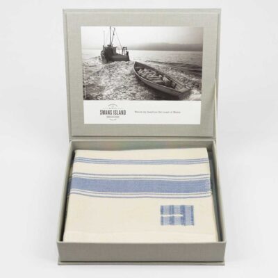 Casa Branca x Swans Island - Branca Stripe Throw . 100% soft merino wool with hand-dyed stripes and ivory silk binding. Handwoven in Maine. Shown here in Sky Blue. Each throw comes in this exclusive grey linen gift box.