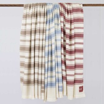 Casa Branca x Swans Island - Branca Stripe Throw in a trio of hand-dyed colors. 100% soft merino wool with ivory silk binding. Handwoven in Maine.