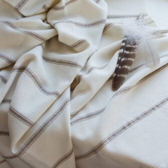 Casa Branca x Swans Island - Branca Ticking Stripe Throw . 100% soft merino wool with hand-dyed stripes and ivory silk binding. Handwoven in Maine. Shown here in Biscotti.